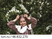 Vintage women's accessories and retro-style clothing. A small, beautiful girl with bows in her hair, in a beige dress and a beret outdoors. Стоковое фото, фотограф Photojuli / Фотобанк Лори