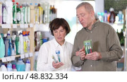 Elderly couple choosing toothbrushes and mint paste in the department with household chemicals in the supermarket. Стоковое видео, видеограф Яков Филимонов / Фотобанк Лори