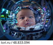 Новорожденный находится в прозрачной капсуле, окруженный медицинскими проводами и цифровыми дисплеями, в затемненной больничной комнате. Легкий свет от внутренних систем освещает лицо. Стоковое AI-изображение, AI-художник Сергей Никифоров-Гордеев / Фотобанк Лори