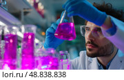 Scientist conducts experiment with vibrant pink liquids in laboratory setting. Стоковое AI-изображение, AI-художник Сергей Толмачёв / Фотобанк Лори