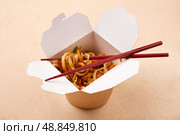 Noodles served in takeout box with chopsticks on a simple background. Стоковое фото, фотограф Виктория Тельминова / Фотобанк Лори