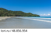 A beautiful tropical beach without people. The waves of the turquoise ocean foam and spread over the sand. Green vegetation on the hill. Blue sky, clouds. Copy space. Malaysia. Borneo. Kota Kinabalu. Стоковое фото, фотограф Вера Ивановна Кубарева / Фотобанк Лори