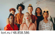 Seven young women of various ethnicities and hairstyles stand in a modern interior space, posing for a photo. Стоковое AI-изображение, AI-художник Данила Большаков / Фотобанк Лори