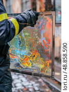 A first responder in uniform is holding up a detailed map of a city while responding to an emergency. The map is likely being used for navigation or to strategize the response. Стоковое AI-изображение, AI-художник Данила Большаков / Фотобанк Лори