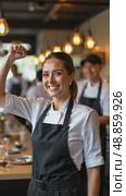 Woman in a black apron is smiling and holding her arm up. Стоковое AI-видео, аниматор Sergey Grishin / Фотобанк Лори