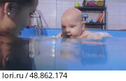 Instructor holding baby underwater during infant swimming lessons. Стоковое видео, видеограф Константин Шишкин / Фотобанк Лори
