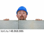 Builder peering over wall. Стоковое фото, агентство Ingram Publishing / Фотобанк Лори