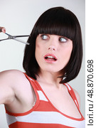 Woman scared of a pair of hairdressing scissors. Стоковое фото, агентство Ingram Publishing / Фотобанк Лори