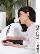 brunet woman  lying on sofa  quill in hand. Стоковое фото, агентство Ingram Publishing / Фотобанк Лори