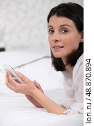 Woman laid on a bed sending text message. Стоковое фото, агентство Ingram Publishing / Фотобанк Лори