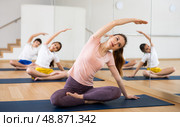 Young woman with preteen children doing stretching exercises in fitness center. Стоковое фото, фотограф Яков Филимонов / Фотобанк Лори