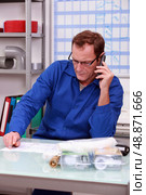 Plumber on the phone in office. Стоковое фото, агентство Ingram Publishing / Фотобанк Лори