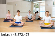 Sporty parents and teenage kids sitting in lotus position in yoga studio. Стоковое фото, фотограф Яков Филимонов / Фотобанк Лори