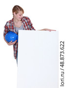 Tradeswoman looking at a blank sign with interest. Стоковое фото, агентство Ingram Publishing / Фотобанк Лори