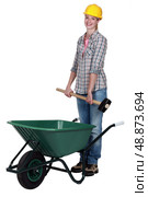 Tradeswoman placing a mallet in a wheelbarrow. Стоковое фото, агентство Ingram Publishing / Фотобанк Лори