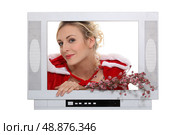Woman dressed in festive outfit coming out of television. Стоковое фото, агентство Ingram Publishing / Фотобанк Лори