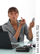 Woman applying lipstick at the office. Стоковое фото, агентство Ingram Publishing / Фотобанк Лори
