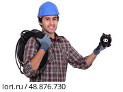 Tradesman holding electric cabling and a piggy bank. Стоковое фото, агентство Ingram Publishing / Фотобанк Лори