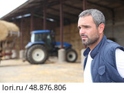 Farmer standing in front of a barn containing a tractor. Стоковое фото, агентство Ingram Publishing / Фотобанк Лори