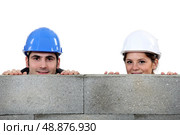 male bricklayer and female counterpart hiding behind wall. Стоковое фото, агентство Ingram Publishing / Фотобанк Лори