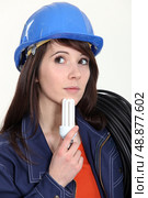 Thoughtful woman holding a compact fluorescent lamp. Стоковое фото, агентство Ingram Publishing / Фотобанк Лори