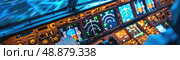 Close-up view of a pilots hand resting on the controls in an airplane cockpit during a night flight. The dashboard is lit up, showing various instruments and gauges. Стоковое AI-изображение, AI-художник Данила Большаков / Фотобанк Лори