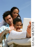 Man, woman and little boy using laptop on a deckchair. Стоковое фото, агентство Ingram Publishing / Фотобанк Лори
