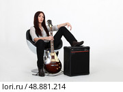 Woman with her foot propped on an amplifier and holding a guitar. Стоковое фото, агентство Ingram Publishing / Фотобанк Лори