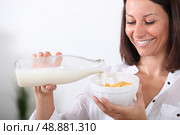Woman pouring milk onto a bowl of cereal. Стоковое фото, агентство Ingram Publishing / Фотобанк Лори