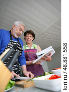 Mature couple cooking with cookbook. Стоковое фото, агентство Ingram Publishing / Фотобанк Лори