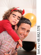 Father giving dressed as devil a piggy-back. Стоковое фото, агентство Ingram Publishing / Фотобанк Лори