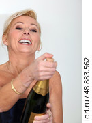 Cheerful woman opening bottle of champagne. Стоковое фото, агентство Ingram Publishing / Фотобанк Лори