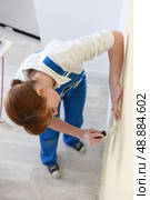 Woman smoothing a wallpaper seam. Стоковое фото, агентство Ingram Publishing / Фотобанк Лори