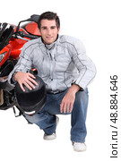 Man kneeling by motor bike. Стоковое фото, агентство Ingram Publishing / Фотобанк Лори