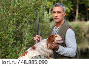 hunter taking a rifle and caressing a hunt dog. Стоковое фото, агентство Ingram Publishing / Фотобанк Лори