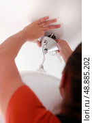 Installing a light fixture. Стоковое фото, агентство Ingram Publishing / Фотобанк Лори
