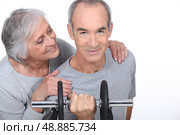 Woman admiring a man lifting a dumbell. Стоковое фото, агентство Ingram Publishing / Фотобанк Лори