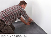 Man laying new carpet in room. Стоковое фото, агентство Ingram Publishing / Фотобанк Лори