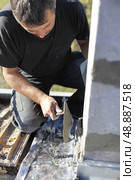 Mason using trowel to spread cement on wall. Стоковое фото, агентство Ingram Publishing / Фотобанк Лори