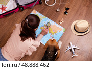 A girl with her dog is exploring the political map, planning a vacation. Стоковое фото, фотограф Виктория Тельминова / Фотобанк Лори
