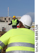 Construction worker watching his colleague using a yardstick. Стоковое фото, агентство Ingram Publishing / Фотобанк Лори