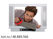 Man with a saw inside a television set. Стоковое фото, агентство Ingram Publishing / Фотобанк Лори