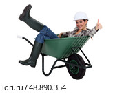 female bricklayer sitting in wheelbarrow thumb up. Стоковое фото, агентство Ingram Publishing / Фотобанк Лори