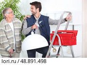 Man putting up a light. Стоковое фото, агентство Ingram Publishing / Фотобанк Лори