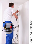 an artisan is pulling down a cable coming from the ceiling. Стоковое фото, агентство Ingram Publishing / Фотобанк Лори
