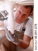 Plumber fixing a siphon. Стоковое фото, агентство Ingram Publishing / Фотобанк Лори