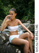 Attractive woman wearing a bikini and drinking water in the forest. Стоковое фото, агентство Ingram Publishing / Фотобанк Лори