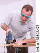 Carpenter with goggles using drill. Стоковое фото, агентство Ingram Publishing / Фотобанк Лори