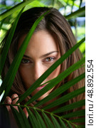 Woman hiding behind plant leaves. Стоковое фото, агентство Ingram Publishing / Фотобанк Лори