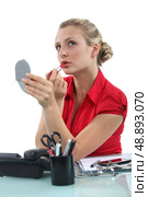 Blond secretary applying lip-stick at her desk. Стоковое фото, агентство Ingram Publishing / Фотобанк Лори
